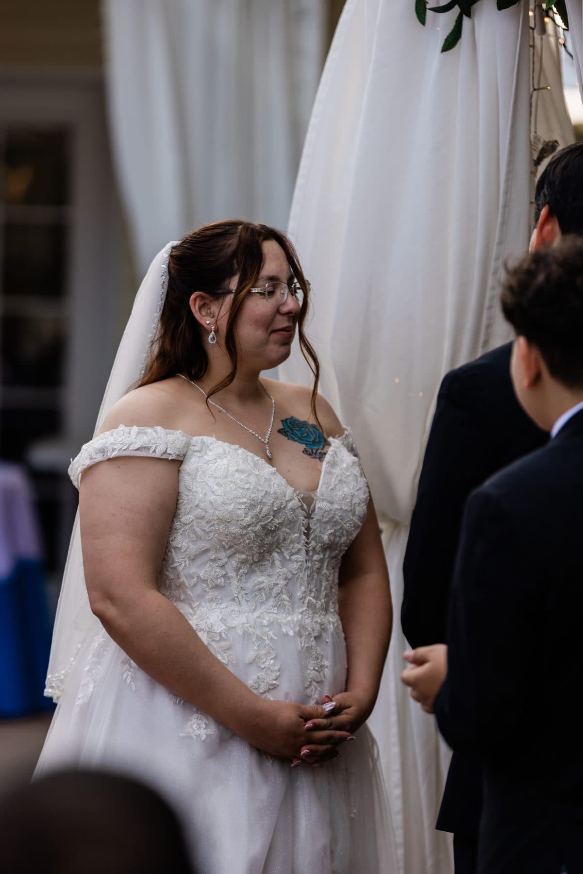 The bride during her vows, white drapery framing the ceremony.