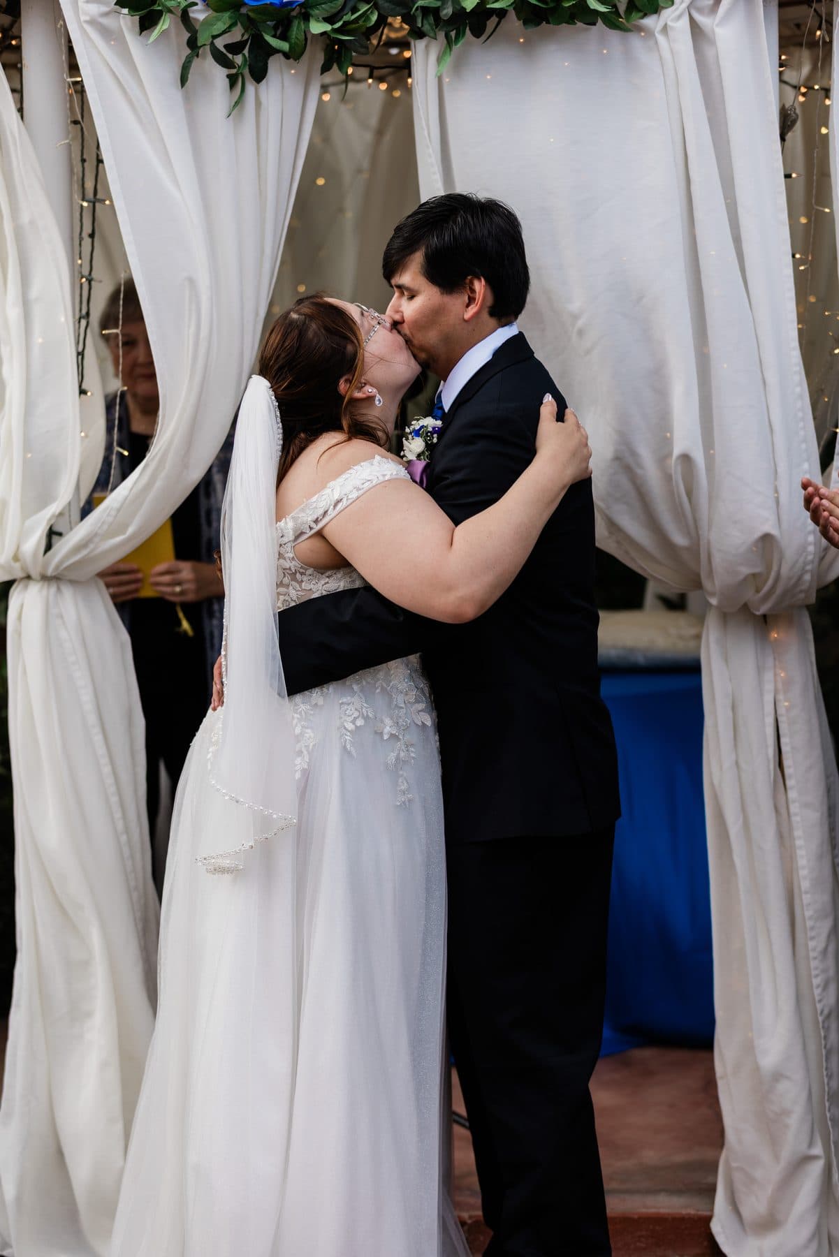 The couple's first kiss under a white draped arch.